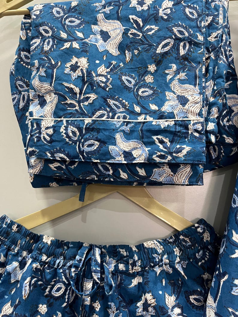 May include: A blue and white floral print pajama set with a drawstring waist and a white trim. The fabric is soft and comfortable.