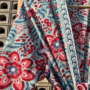 May include: A blue and red floral print cotton robe with a white trim. The robe has a long sleeve and a tie closure.