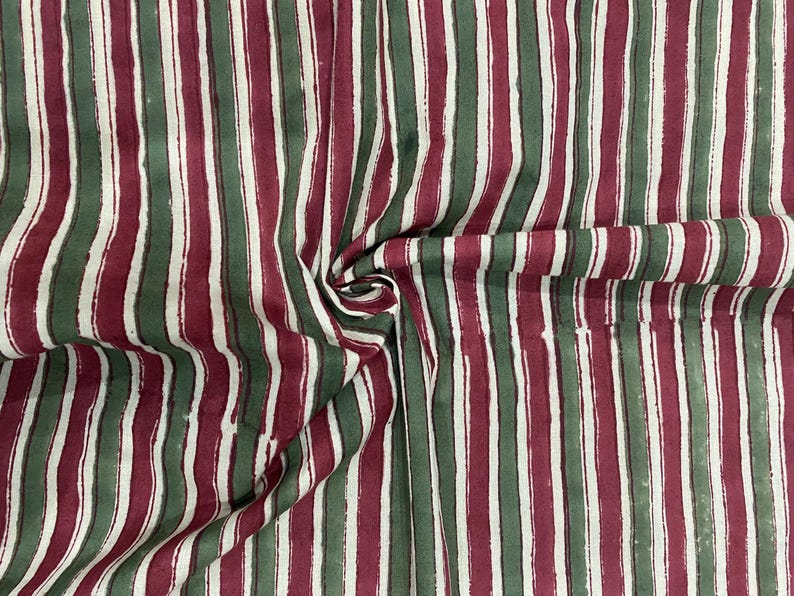 May include: Striped fabric with alternating red and green stripes. The fabric has a white background and the stripes are a darker shade of red and green.