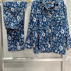 May include: A blue and white floral print pajama set with long sleeves and pants. The set has a button-up front and a collared neckline.