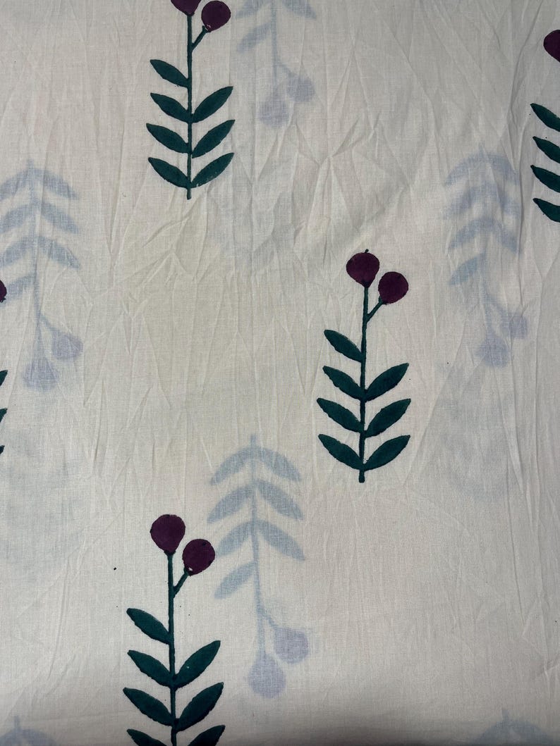 May include: Cream-colored fabric with a repeating pattern of stylized floral elements. Dark green leaves and stems support clusters of two or three deep purple berries. Faint blue-gray leaf shapes are also scattered across the fabric.