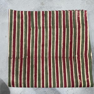 May include: Striped fabric in shades of red, green, and cream. The fabric has a hand-painted look with uneven stripes.