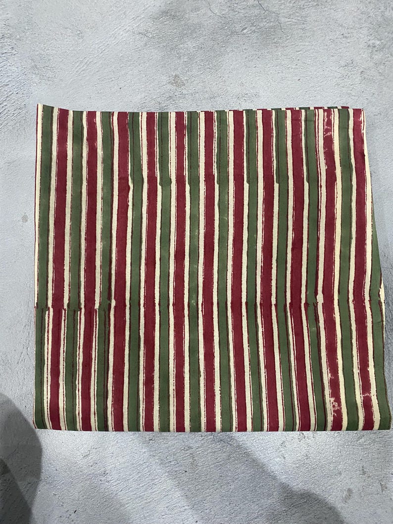 May include: Striped fabric in shades of red, green, and cream. The fabric has a hand-painted look with uneven stripes.