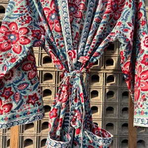 May include: A blue and red floral print cotton robe with a tie waist and two pockets. The robe has a traditional Japanese kimono style.
