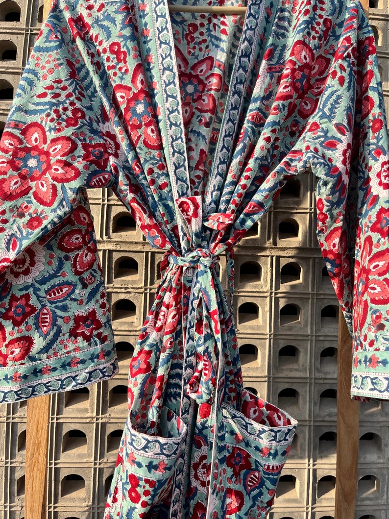 May include: A blue and red floral print cotton robe with a tie waist and two pockets. The robe has a traditional Japanese kimono style.