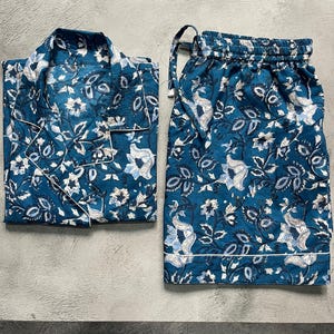 May include: A blue and white floral print pajama set with a button-up top and drawstring shorts.
