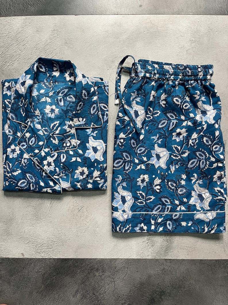 May include: A blue and white floral print pajama set with a button-up top and drawstring shorts.