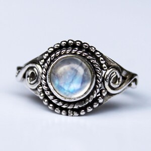 Può includere: Un anello d'argento con una pietra di luna rotonda incastonata in un design a filigrana decorativo.