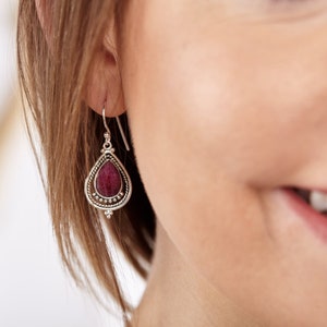 Può includere: Orecchini pendenti in argento con una pietra rossa a forma di lacrima.