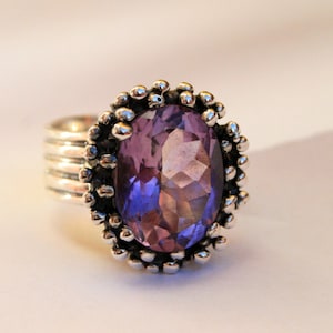 Puede incluir: Un anillo de plata con una gran amatista púrpura facetada engastada en un engaste decorativo con cuentas.