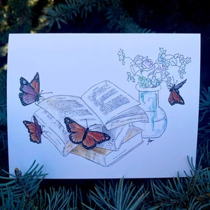 May include: A watercolor illustration of an open book with butterflies flying around it. A vase with flowers sits next to the book. The illustration is on a white background.