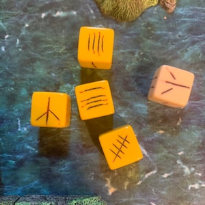 May include: Five yellow dice with black markings on each side. The dice are on a blue and green surface.