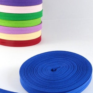 Puede incluir: Una cinta de algodón de sarga azul, enrollada y lista para usar en proyectos de costura o manualidades. La cinta tiene 25 mm de ancho y es un material versátil para una variedad de aplicaciones.