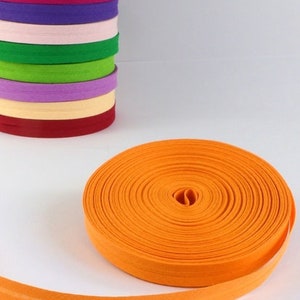 Puede incluir: Primer plano de un rollo de tejido elástico de color naranja brillante. El tejido está enrollado y tiene una textura lisa y uniforme. El tejido es una opción popular para proyectos de costura y manualidades.