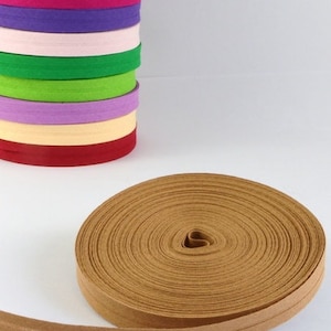Puede incluir: Un cordón de algodón marrón, enrollado y listo para ser utilizado en proyectos de manualidades. El cordón es de doble pliegue, con un color marrón ligeramente más claro en el interior.