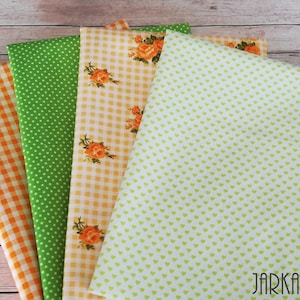 Op de afbeelding: Vier stofstalen in verschillende patronen: oranje en wit ruitjes, groen met witte stippen, oranje en wit ruitjes met oranje bloemenprint en lichtgroen met kleine witte hartjes.