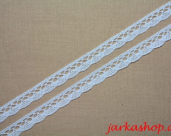 May include: Two strips of white lace with a delicate, openwork design. The lace has a scalloped edge and is set against a tan background. The text "jarkashop.de" is in the bottom right corner.