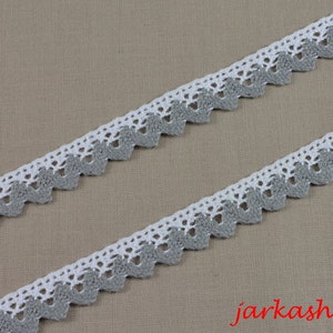 Può includere: Bordino in crochet bianco e grigio con un bordo a festoni. Il bordino è in cotone e largo circa 2,5 cm.