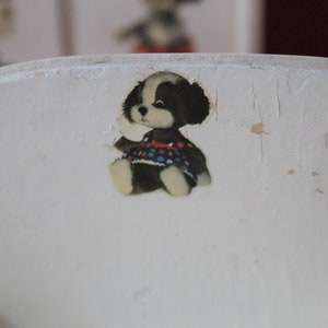 May include: White wooden chair with a black and white puppy sticker wearing a colourful polka dot dress.