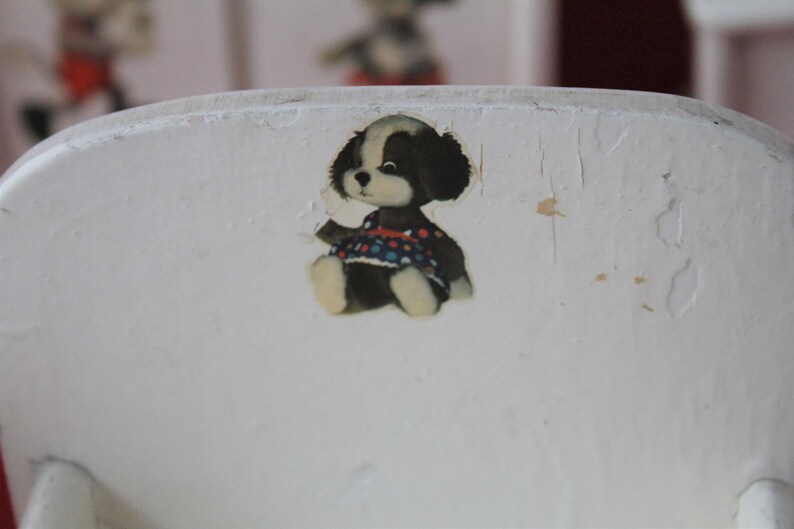May include: White wooden chair with a black and white puppy sticker wearing a colourful polka dot dress.