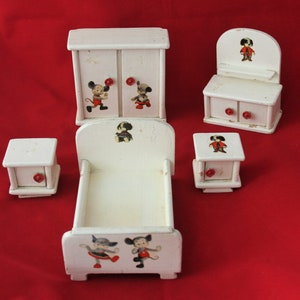 May include: A white wooden dollhouse furniture set with a bed, dresser, wardrobe, and two bedside tables. The furniture is decorated with cartoon characters, including Mickey Mouse and Pluto.