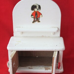 May include: White wooden toy cabinet with two doors and a shelf. The cabinet has a black and white dog illustration on the front.
