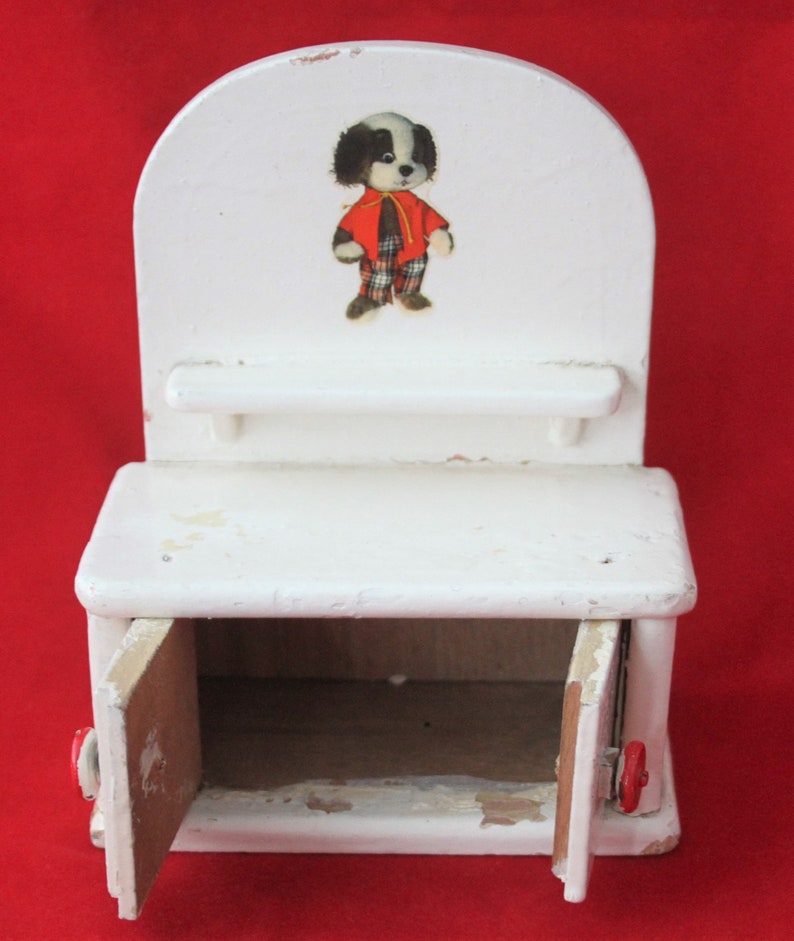 May include: White wooden toy cabinet with two doors and a shelf. The cabinet has a black and white dog illustration on the front.