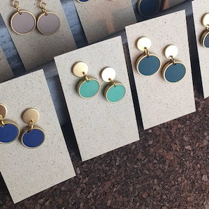 Puede incluir: Surtido de pendientes circulares dorados y de colores expuestos en tarjetas. Los pendientes presentan una variedad de colores, incluyendo azul, verde y marr&oacute;n.