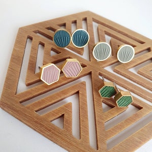 Peut inclure: Un ensemble de six boucles d'oreilles à clous hexagonales et rondes avec des motifs géométriques. Les boucles d'oreilles sont en métal doré et présentent une variété de couleurs, notamment le vert, le rose et le gris.