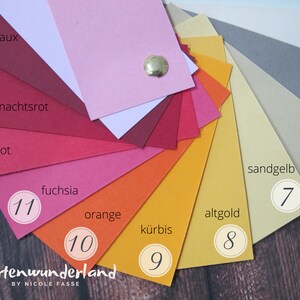 Peut inclure: Une roue de couleurs avec 11 nuances diff&eacute;rentes de rouge, orange et jaune. Les couleurs sont &eacute;tiquet&eacute;es en allemand avec les num&eacute;ros 7 &agrave; 11. Le texte "Kartenwunderland BY NICOLE FASSE" est en bas de l'image.