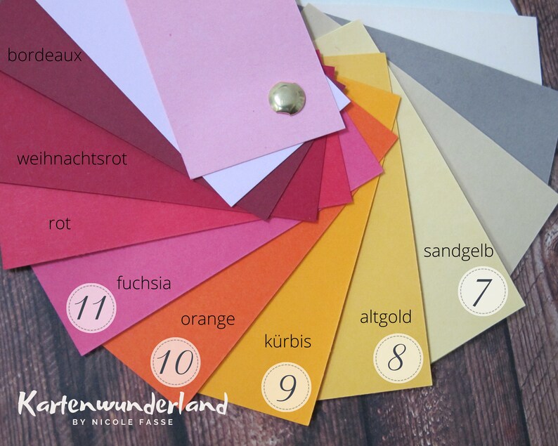 Peut inclure: Une roue de couleurs avec 11 nuances diff&eacute;rentes de rouge, orange et jaune. Les couleurs sont &eacute;tiquet&eacute;es en allemand avec les num&eacute;ros 7 &agrave; 11. Le texte "Kartenwunderland BY NICOLE FASSE" est en bas de l'image.