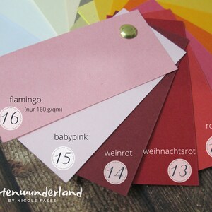 May include: A color chart of paper samples in shades of pink and red. The colors are labeled with German names: flamingo, baby pink, weinrot, weihnachtsrot, and rot. Each color has a number next to it, ranging from 12 to 16.