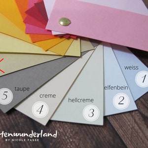 May include: A color chart of 10 different shades of paper, ranging from bright orange to light blue. The paper is arranged in a fan shape, with the darkest shade at the top and the lightest shade at the bottom. The shades are labeled with numbers 1 through 5 and the names "weiss", "elfenbein", "hellcreme", "creme", and "taupe".