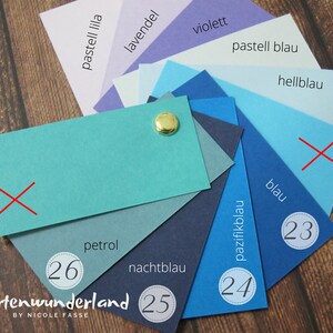 May include: A color chart with 10 different shades of blue, from light blue to dark blue. The chart is labeled with the German names for each color, including "pastell blau", "hellblau", "blau", "pazifikblau", "nachtblau", "petrol", "lavendel", "violett", and "pastell lila". The chart also includes numbers 23, 24, 25, and 26.
