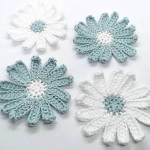 May include: Four crocheted flowers, two white and two light blue, with a white centre and a light blue centre.
