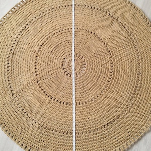 Puede incluir: Una alfombra redonda de yute en tono natural, con un di&aacute;metro aproximado de 120 cm. La alfombra presenta c&iacute;rculos conc&eacute;ntricos y patrones decorativos calados. Una cinta m&eacute;trica se coloca en el centro. La alfombra est&aacute; sobre una superficie clara.