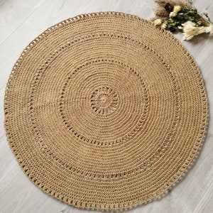 Puede incluir: Una alfombra redonda de yute beige con un dise&ntilde;o en espiral. La alfombra est&aacute; tejida a mano con una superficie texturizada y costuras decorativas. La alfombra mide aproximadamente 122 cm de di&aacute;metro, adecuada para una sala de estar o dormitorio.