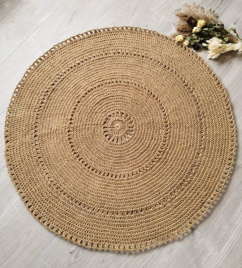 Puede incluir: Una alfombra redonda de yute beige con un dise&ntilde;o en espiral. La alfombra est&aacute; tejida a mano con una superficie texturizada y costuras decorativas. La alfombra mide aproximadamente 122 cm de di&aacute;metro, adecuada para una sala de estar o dormitorio.