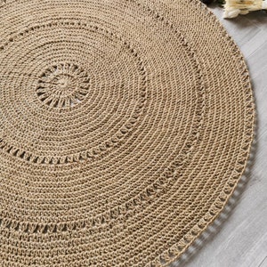 Puede incluir: Una alfombra redonda beige tejida con un dise&ntilde;o en espiral. La alfombra est&aacute; hecha de fibras naturales y tiene una superficie texturizada. El di&aacute;metro de la alfombra es de aproximadamente 152 cm.