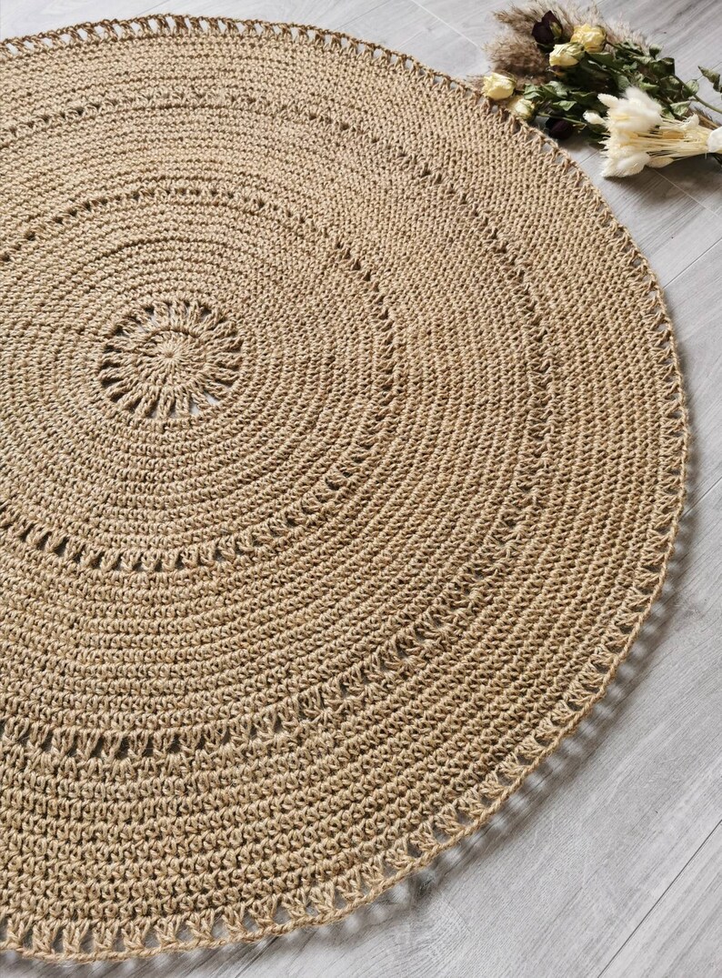 Puede incluir: Una alfombra redonda beige tejida con un dise&ntilde;o en espiral. La alfombra est&aacute; hecha de fibras naturales y tiene una superficie texturizada. El di&aacute;metro de la alfombra es de aproximadamente 152 cm.