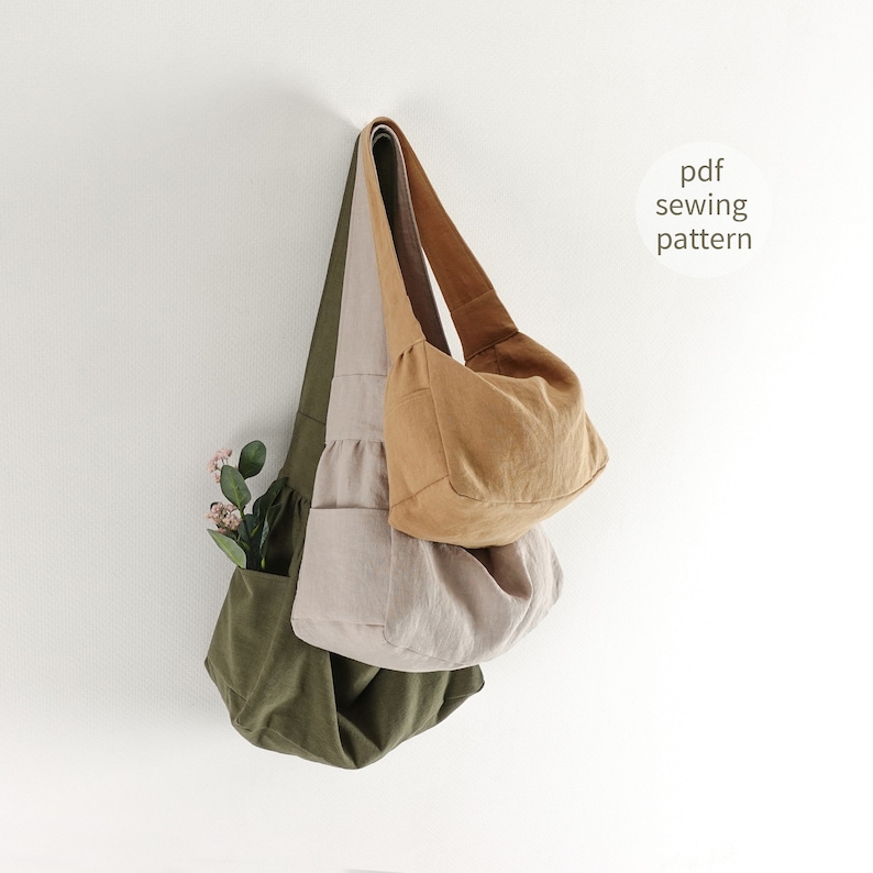 May include: Three fabric bags in different colors: olive green, beige, and brown. The bags are hanging on a white wall. The bags are all made of a soft, natural fabric. The text "pdf sewing pattern" is written in black on a white background.