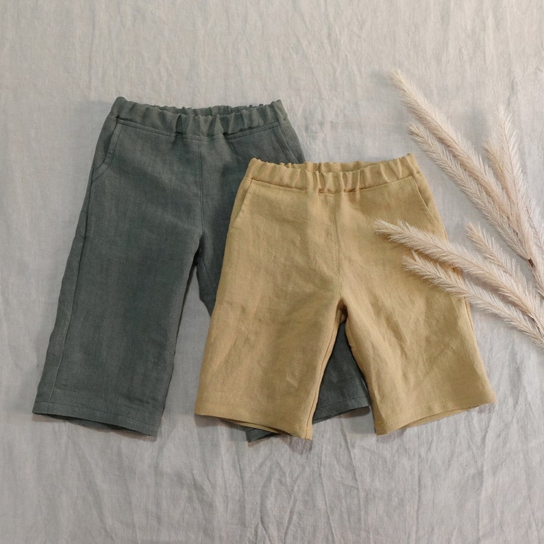 Pode incluir: Dois pares de cal&ccedil;&otilde;es de linho, um na cor verde escuro e o outro na cor amarelo claro. Ambos os cal&ccedil;&otilde;es t&ecirc;m um caimento descontra&iacute;do e um design simples.