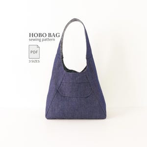 Pode incluir: Uma bolsa hobo de ganga azul escura com uma alça de ombro única e um bolso frontal. O texto diz HOBO BAG sewing pattern, PDF e 3 SIZES. A bolsa tem uma silhueta triangular estruturada com costuras visíveis ao longo das bordas.