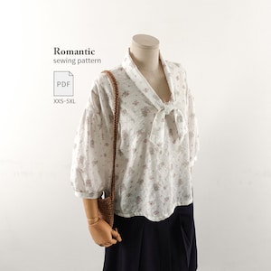 Puede incluir: Una blusa blanca con un pequeño estampado floral rosa, con escote en V con detalle de lazo y mangas abullonadas de tres cuartos. El texto "Romantic sewing pattern", "PDF" y "XXS-5XL" es visible en la parte superior izquierda.