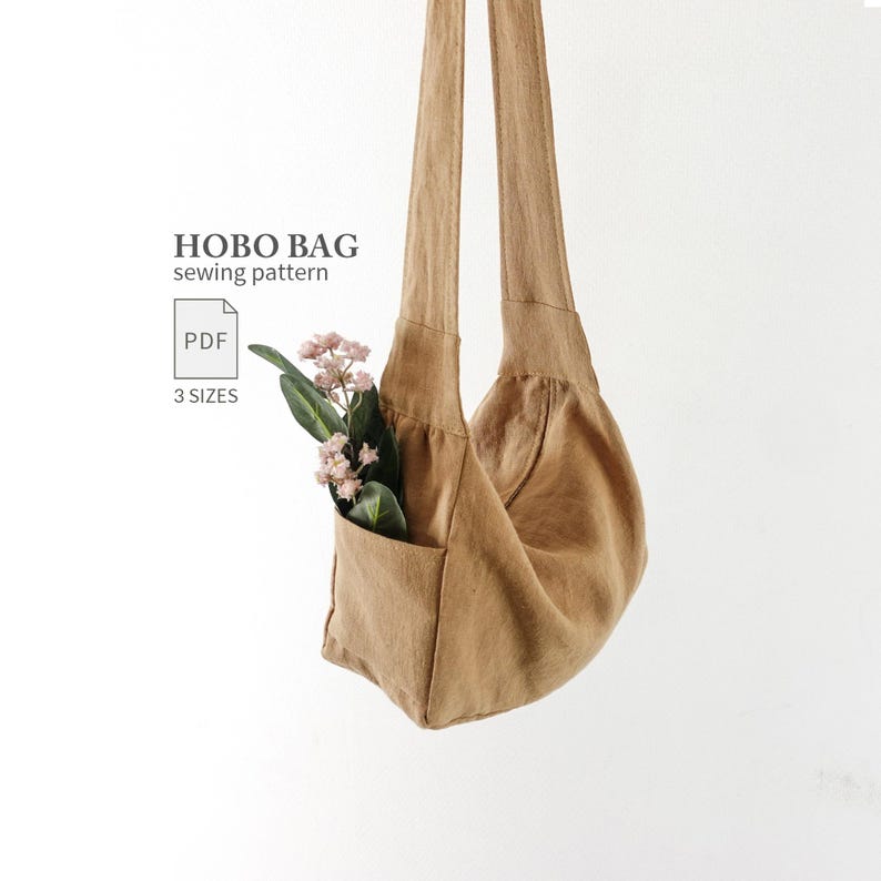 May include: A tan hobo bag with a single shoulder strap and an external pocket containing a small sprig of pink flowers. The text HOBO BAG sewing pattern, a PDF icon, and the words 3 SIZES are printed on the left side of the image.