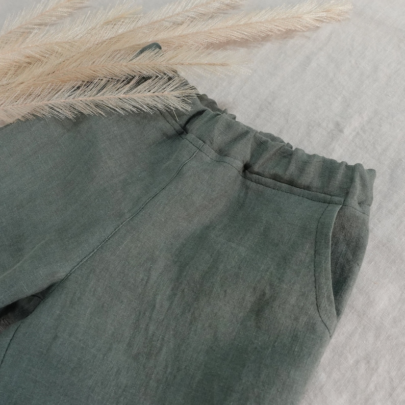 Pode incluir: Uma cal&ccedil;a de linho verde escuro com uma cintura larga e um bolso do lado direito.
