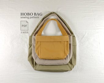 May include: A digital sewing pattern for a hobo bag, featuring text that reads HOBO BAG sewing pattern, PDF, and 3 SIZES. The image displays three nested hobo bags in mustard yellow, light beige, and olive green, each with a single shoulder strap.