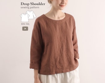 Może przedstawiać: Brązowa bluzka z długim rękawem, okrągłym dekoltem i obniżoną linią ramion. Widoczny jest napis Drop Shoulder sewing pattern XXS-5XL oraz rysunek techniczny odzieży. Bluzka ma podwinięte rękawy i luźny krój.