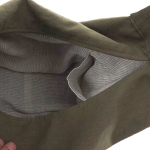 May include: A green linen tote bag with a light gray striped lining. The bag has a single pocket on the inside.