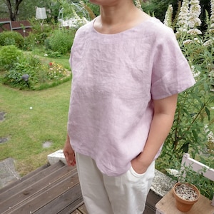 Op de afbeelding: Een licht roze linnen top met korte mouwen en een ronde hals. De top is losjes gesneden en heeft een ontspannen, casual stijl.